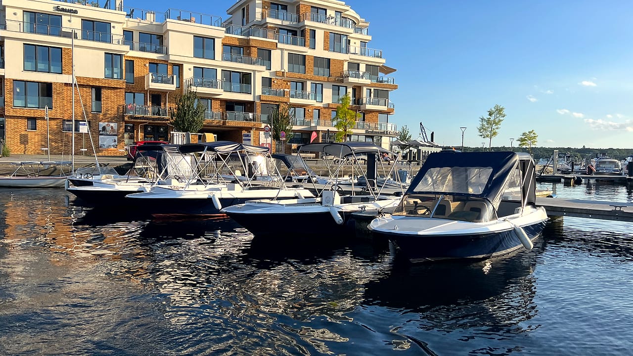 Motorboote am Steg im Stadthafen Waren in der Abendstimmung, im Hintergrund die Hafenpromenade.