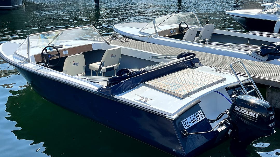 Führerscheinfreies Motorboot (Typ 1) in Blau-Weiß mit Windschutzscheibe, Steuerstand und Suzuki-Außenborder am Steg im Stadthafen Waren an der Müritz.