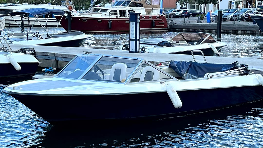 Führerscheinfreies Motorboot (Typ 2) in Dunkelblau-Weiß mit Windschutzscheibe und zwei Sitzen am Steg im Stadthafen Waren.